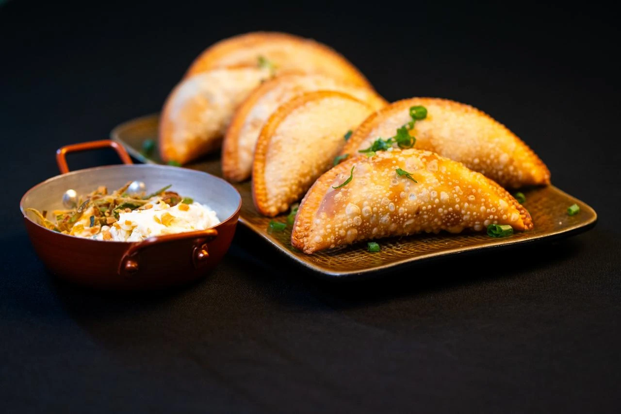 Pastéis dourados do MAWI com creme temperado numa travessa escura